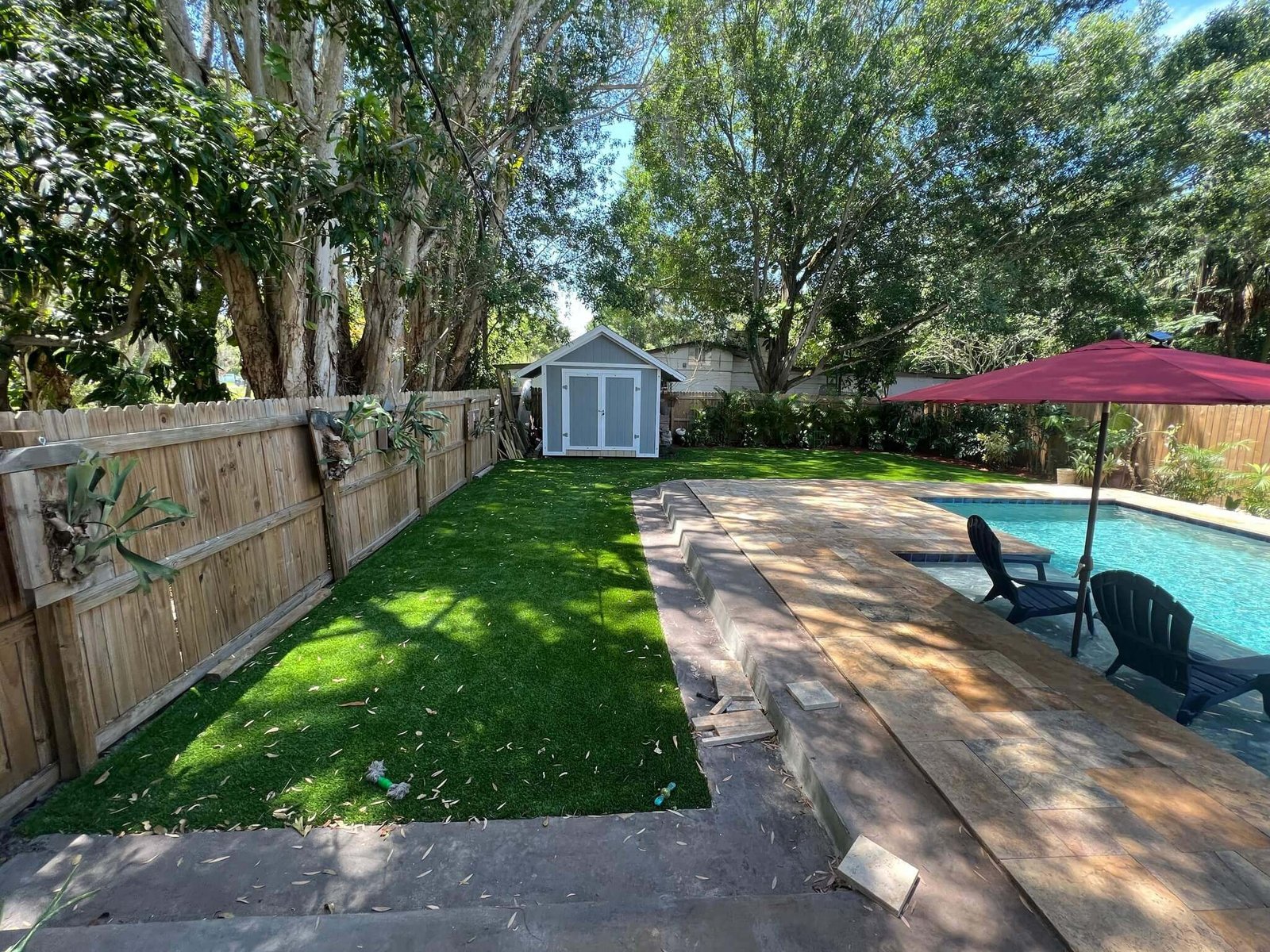 Fenced backyard with artificial turf beside a pool, installed by ProTurf Solutions