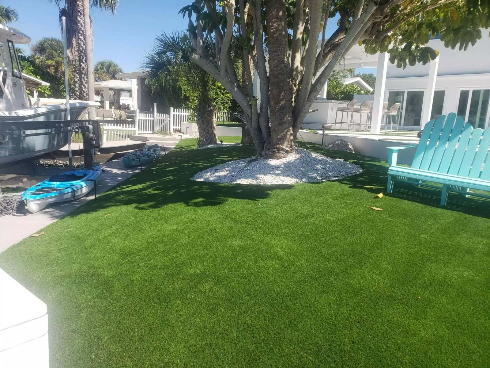 Backyard artificial turf around a shade tree beside a canal, installed by ProTurf Solutions