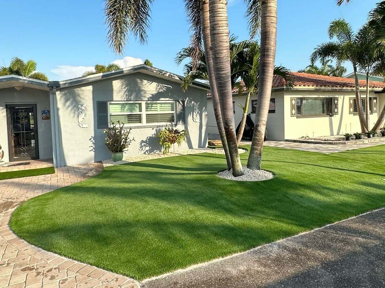 Front yard artificial turf with a stone ring around a palm tree, installed by ProTurf Solutions