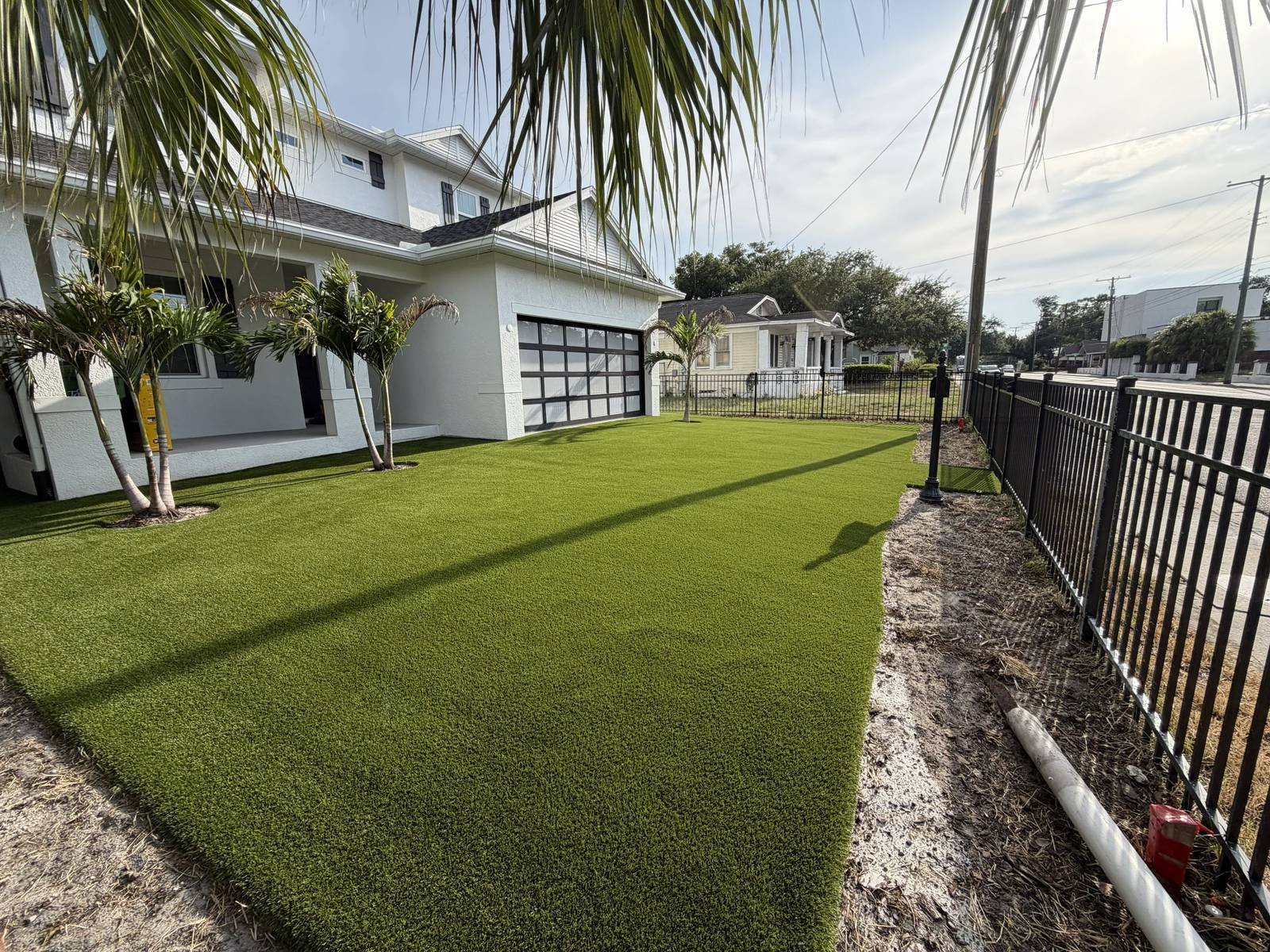 Side yard artificial turf along a black metal fence at a modern home, installed by ProTurf Solutions