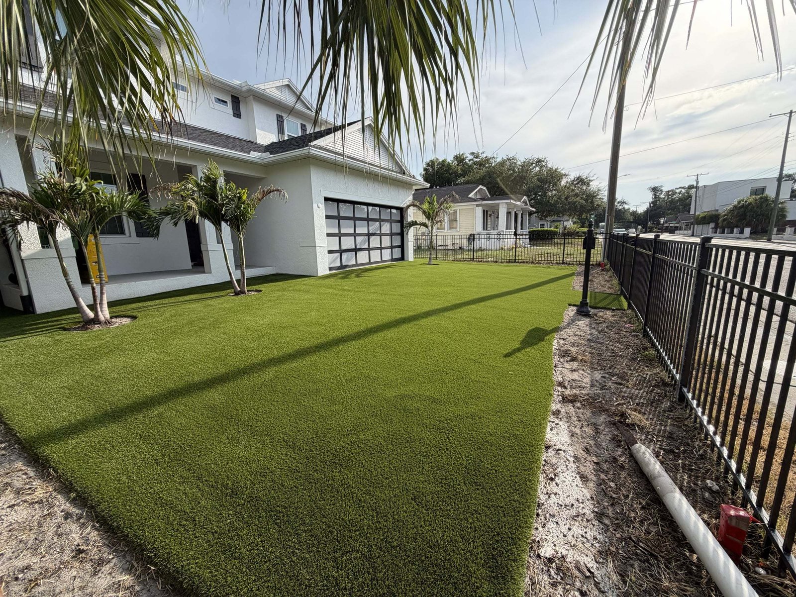 Side yard artificial turf along a black metal fence at a modern home, installed by ProTurf Solutions