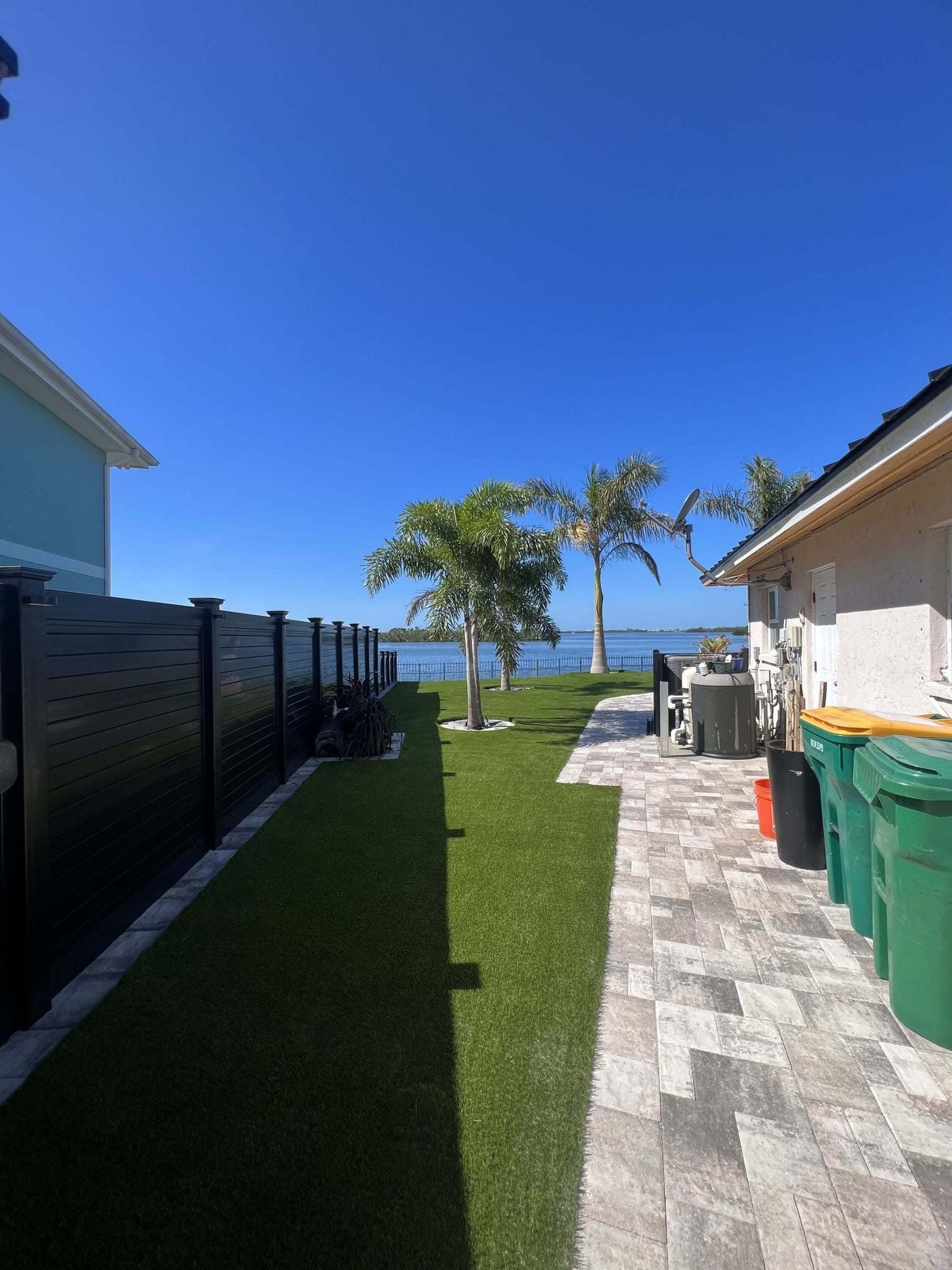 Side yard artificial turf along a paver walkway, installed by ProTurf Solutions